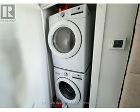 A white washing machine is stacked on top of another white washing machine in a small space.