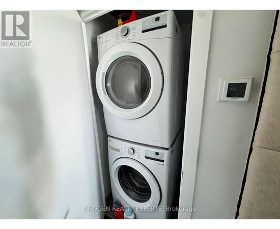 A white washing machine is stacked on top of another white washing machine in a small space.