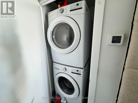 A white washing machine is stacked on top of another white washing machine in a small space.