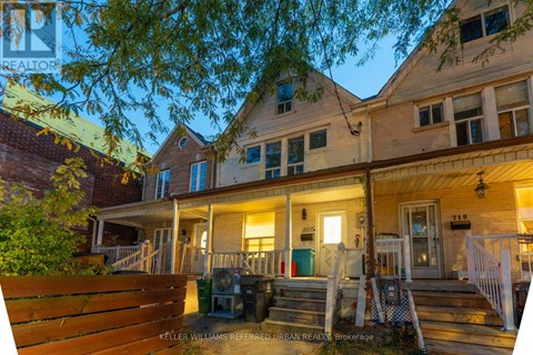 A house with a porch and a tree in front of it.