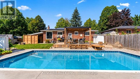 A pool in a backyard with a deck and a house in the background.