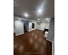 A spacious room with wooden flooring and white walls.