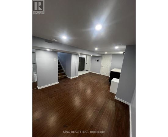 A spacious room with wooden flooring and white walls.