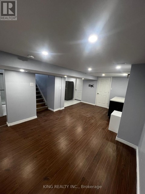 A spacious room with wooden flooring and white walls.