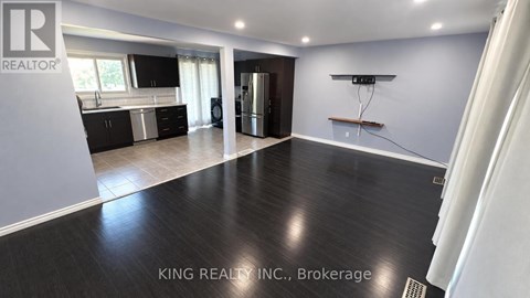 A spacious kitchen with dark wood flooring and modern appliances.