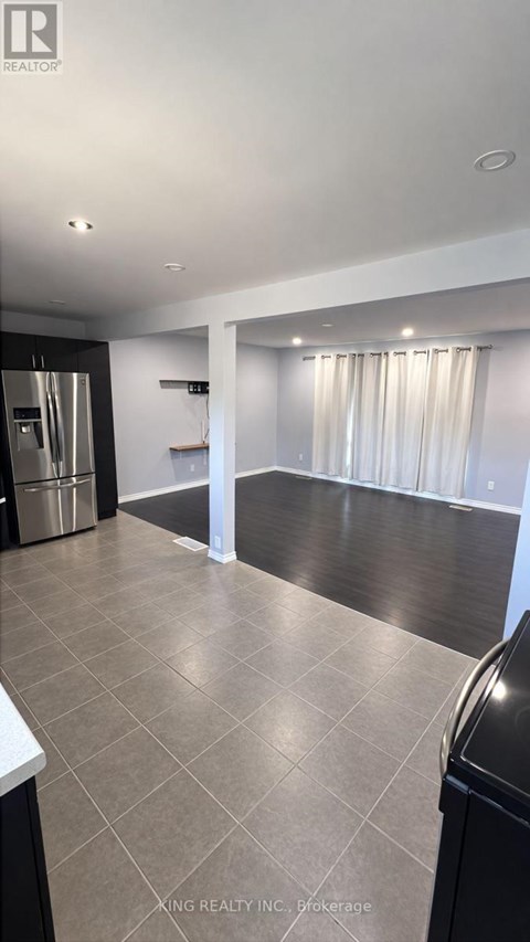 A kitchen with a black fridge and a black trash can.