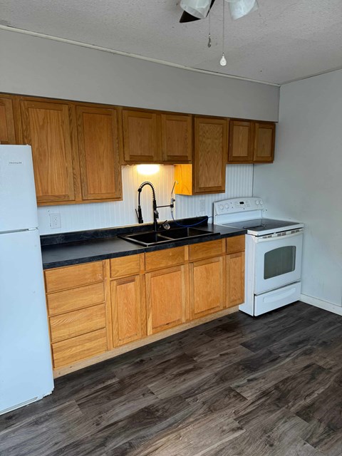 A kitchen with wooden cabinets and white appliances.
