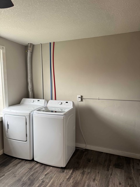 A pair of white front load washing machines in a laundry room.