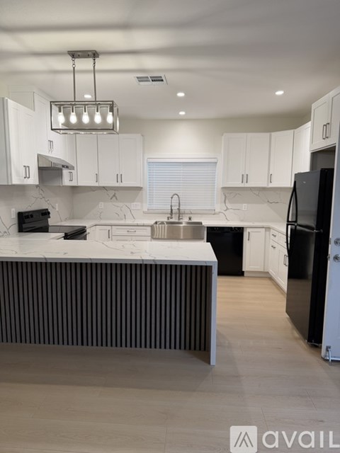 A modern kitchen with black appliances and white cabinets.