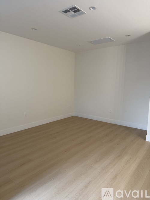 A room with wooden flooring and white walls.