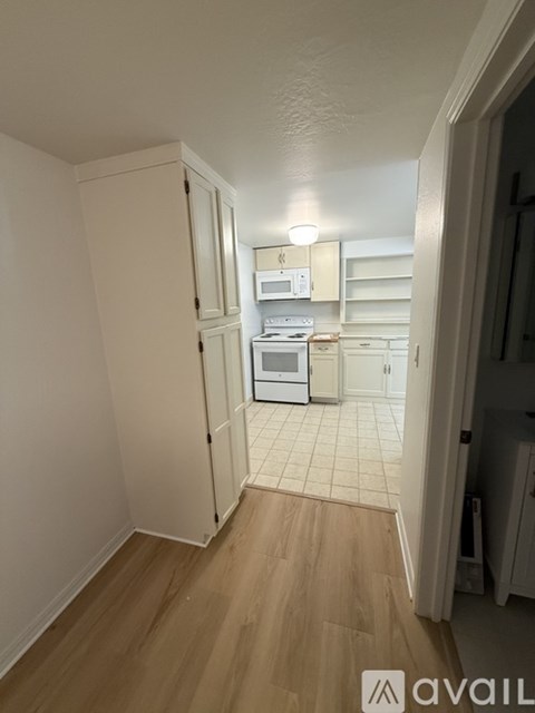A kitchen with white cabinets and appliances in a small room.