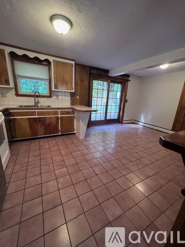 A kitchen with brown tile flooring and wooden cabinets.