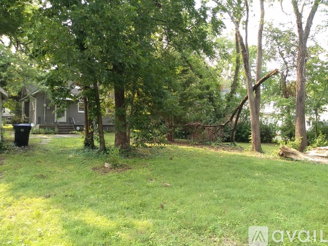 A grassy area with trees and a house in the background.
