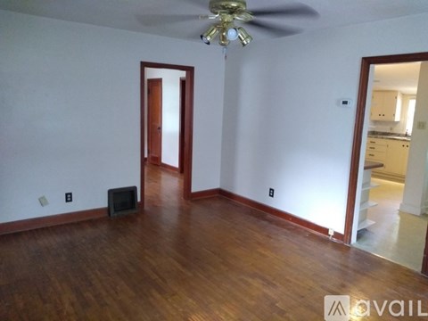 A room with a ceiling fan and wooden floors.