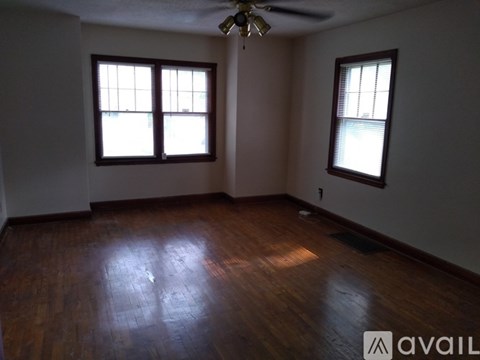 A room with wooden floors and two windows.