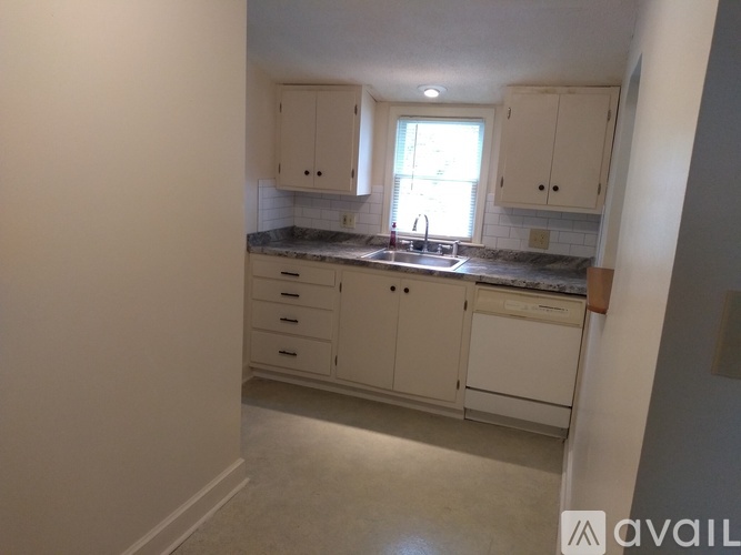 A kitchen with white cabinets and a window above the sink.