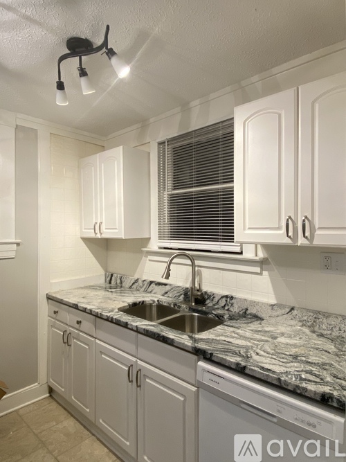 A kitchen with white cabinets and a marble countertop.