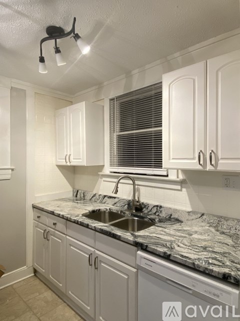 A kitchen with white cabinets and a marble countertop.
