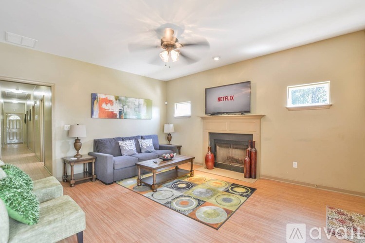 A living room with a grey couch and a Netflix sign on the wall.