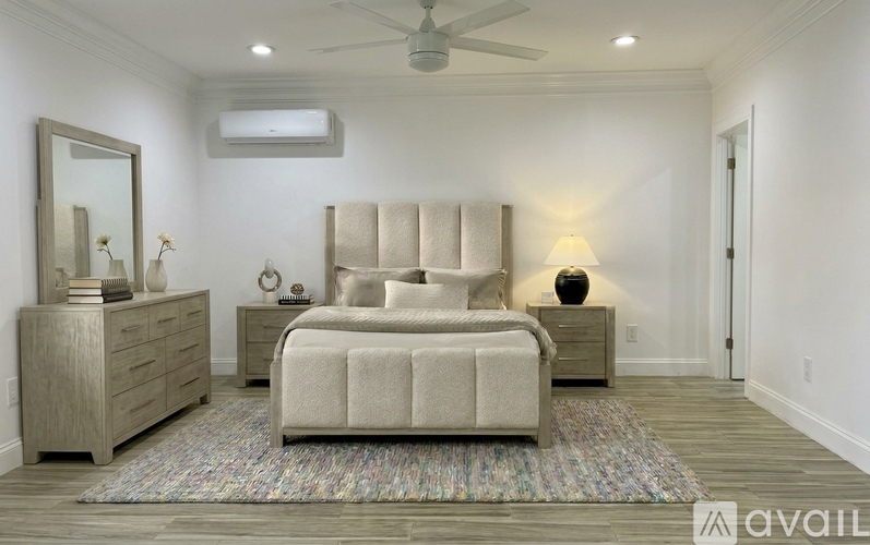 A bedroom with a large bed, a dresser, and a mirror.