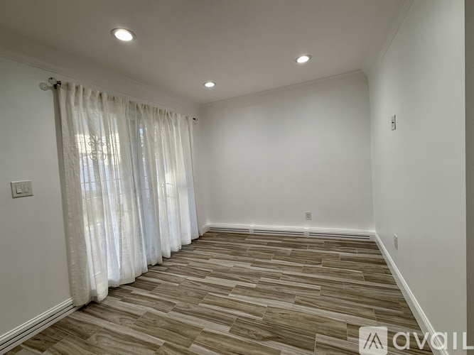 A room with wooden flooring and white walls.
