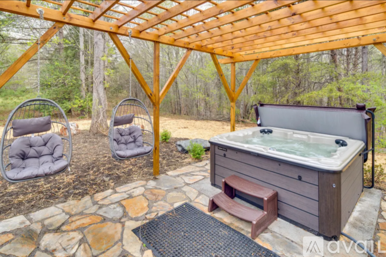 A hot tub is surrounded by a wooden pergola and two chairs.