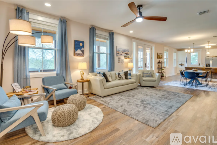 A spacious living room with a blue chair, a white sofa, and a rug on the floor.