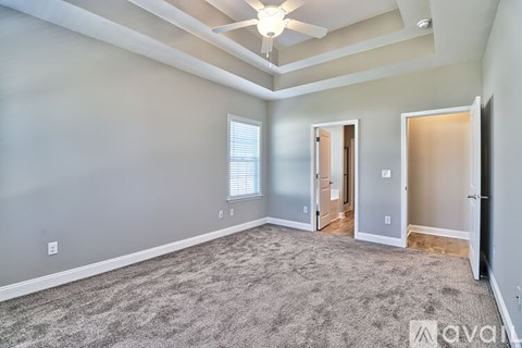 A spacious room with a carpeted floor and a ceiling fan.