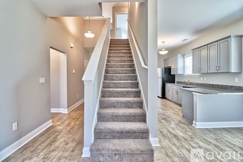 A staircase with a carpeted runner leads up to a kitchen area.
