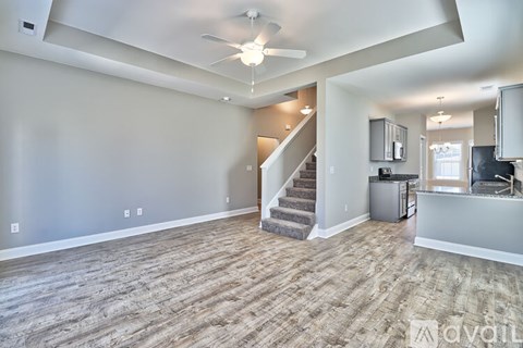 A spacious living room with a staircase leading to the upper level.