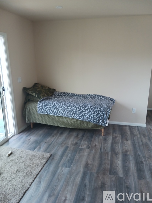A bedroom with a bed and a rug on the floor.