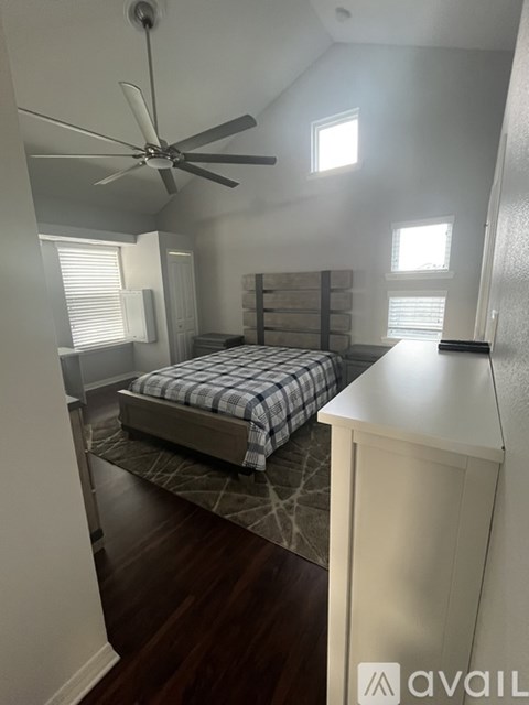 A bedroom with a bed, dresser, and ceiling fan.