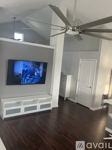 A modern living room with a television and a ceiling fan.