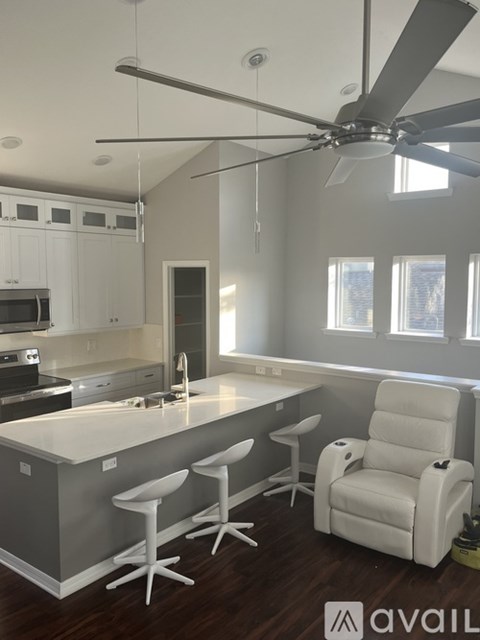 A kitchen with white cabinets and a white chair.