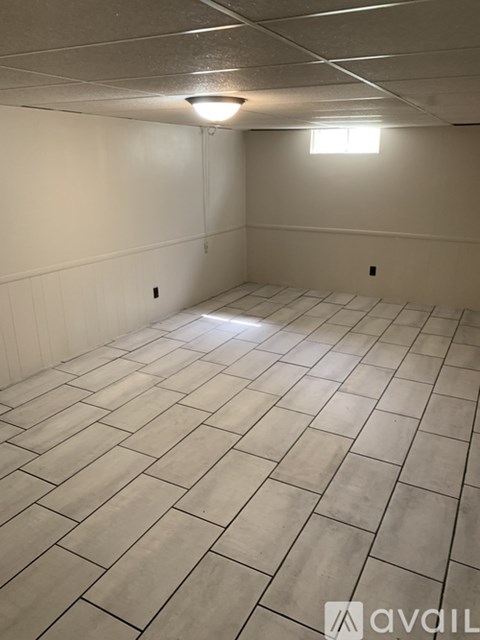 A room with a tiled floor and a window on the wall.