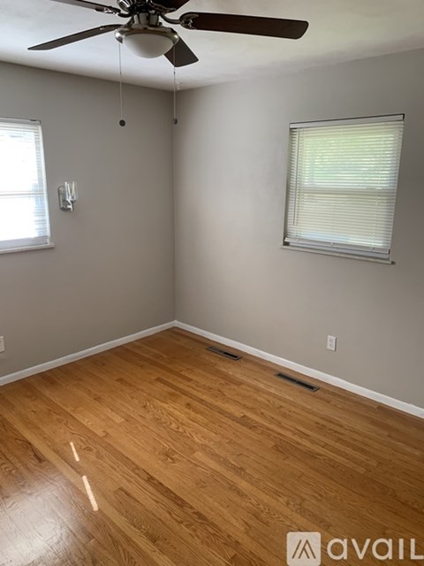 A room with a ceiling fan and wooden flooring.