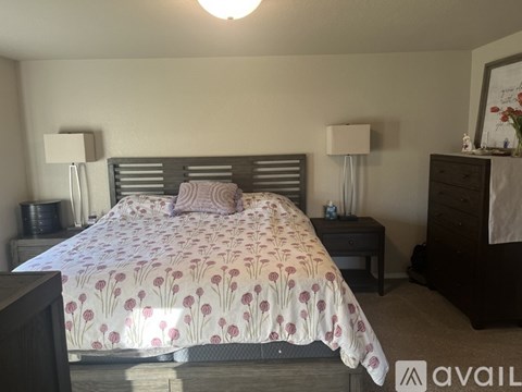 A bedroom with a large bed and two lamps.