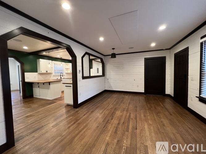 A spacious room with wooden flooring and white walls.