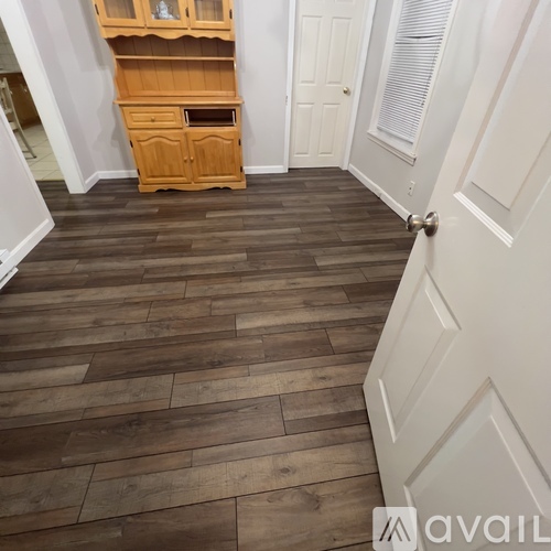 A room with wooden flooring and a wooden cabinet.