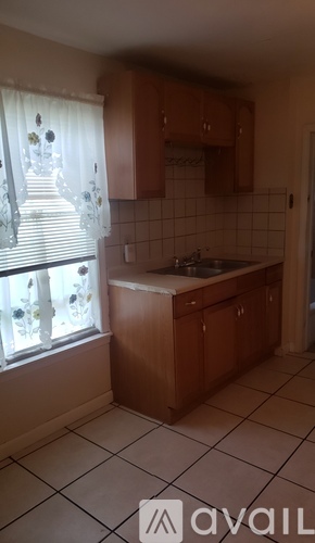 A kitchen with wooden cabinets and a tiled floor.