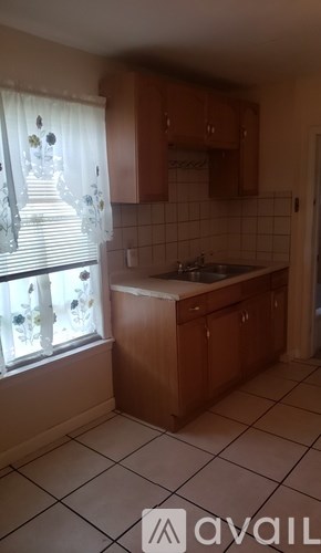 A kitchen with wooden cabinets and a tiled floor.