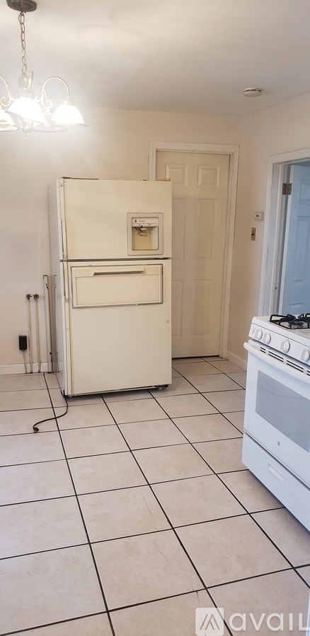 A white fridge and stove in a kitchen with tiled floors.