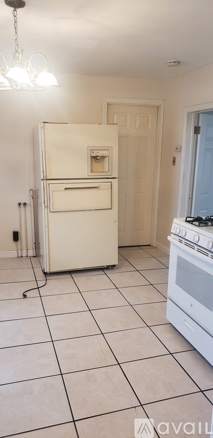 A white fridge and stove in a kitchen with tiled floors.