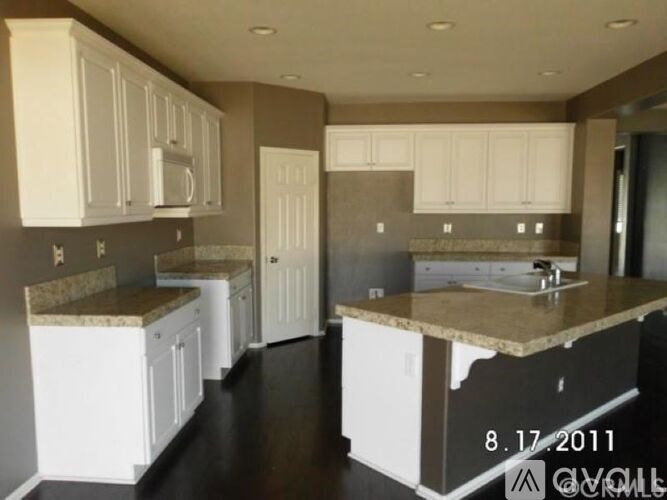 A kitchen with white cabinets and a marble countertop.