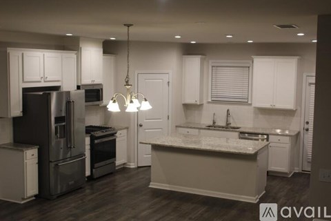 A kitchen with white cabinets and a marble countertop.