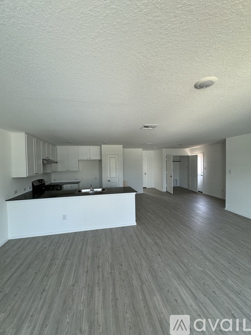 A spacious kitchen with white cabinets and a black countertop.