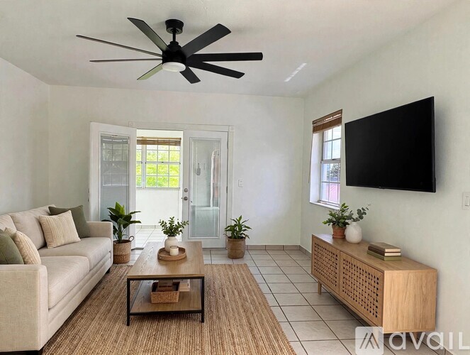 A living room with a beige couch, a ceiling fan, and a wooden cabinet.