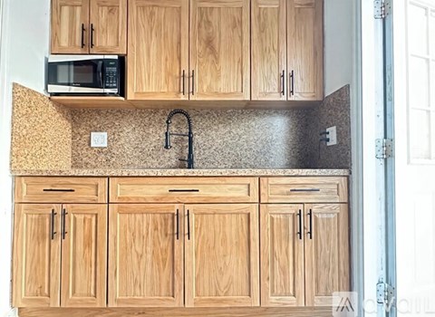 A kitchen with wooden cabinets and a microwave above the counter.