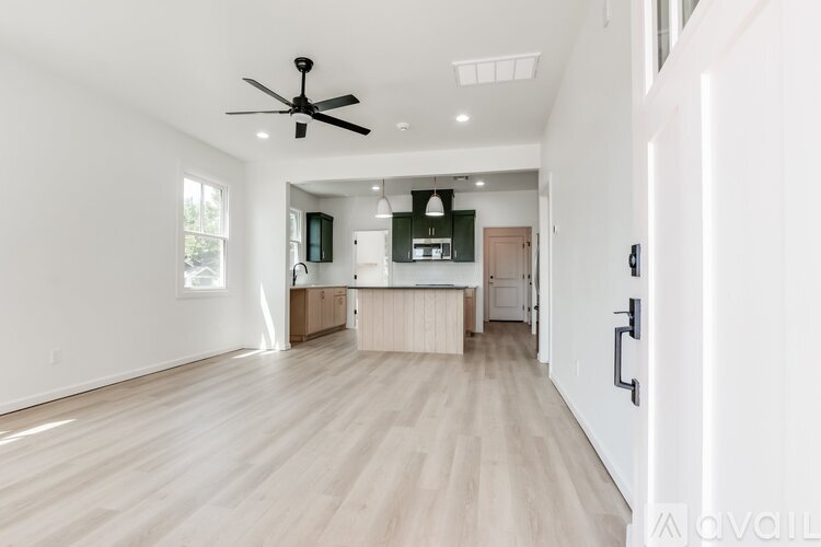 A spacious living room with a ceiling fan and lighting.
