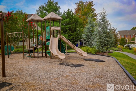 A playground with a green slide and a brown swing set.